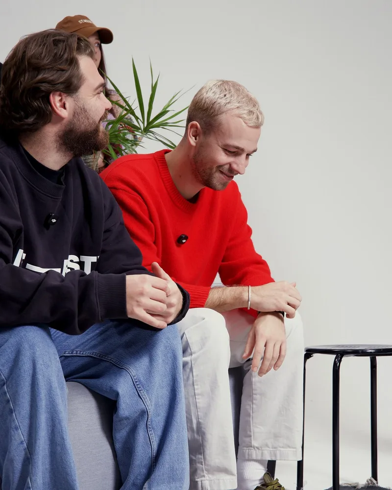 Nikolaus Feist und Lukas Renner lachen zusammen auf dem Sofa