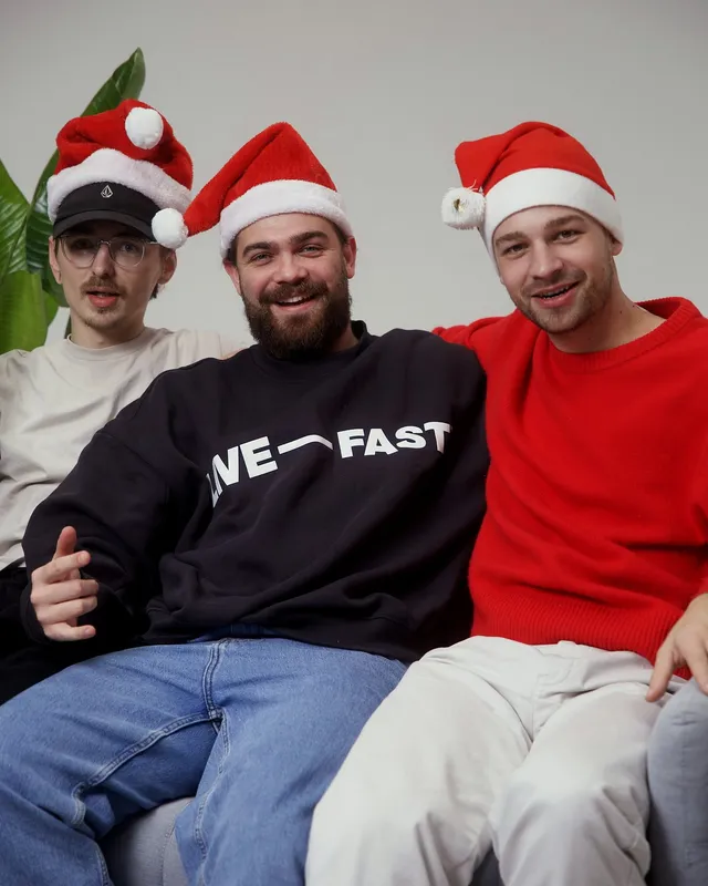 Nikolaus Feist, Lukas Renner und ein Kollege mit Weihnachtsmützen auf dem Sofa
